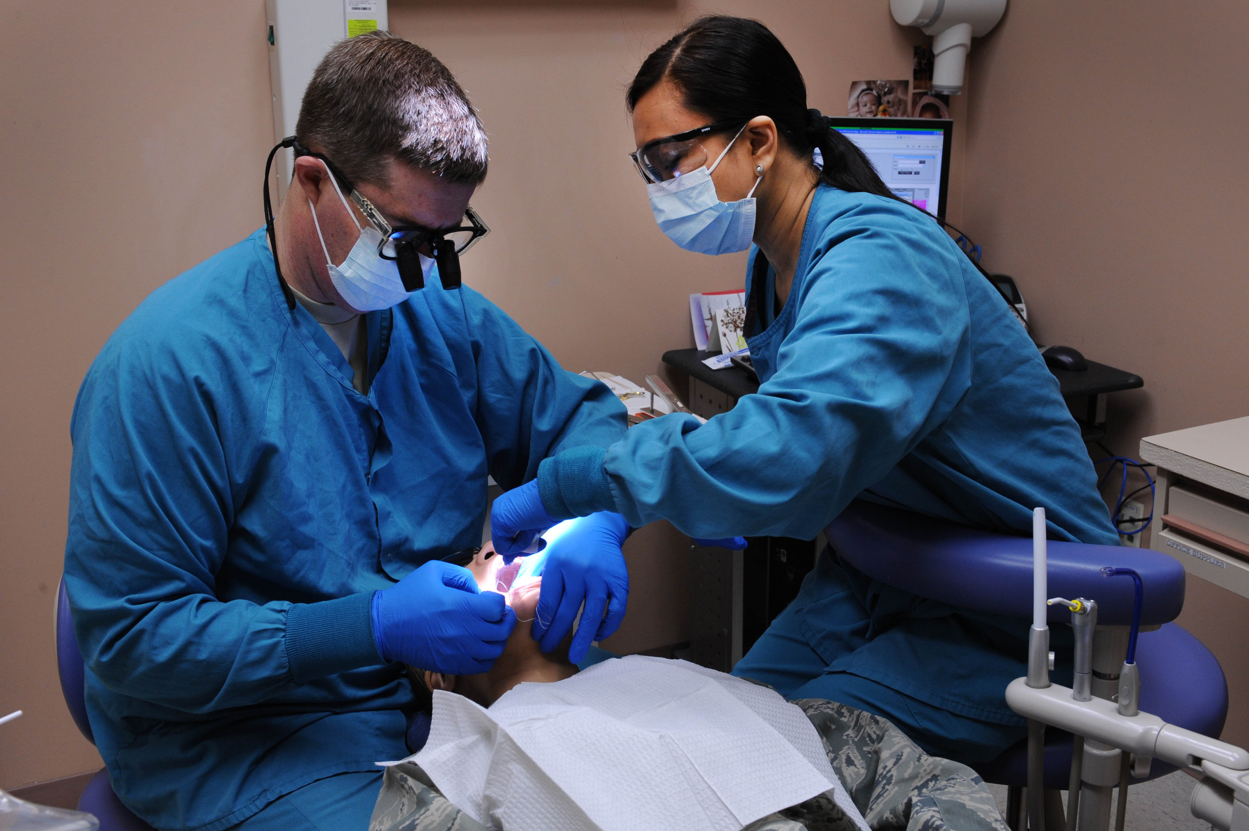 NELLIS AIR FORCE BASE, Nev.-- Maj. Matthew Huffaker, 99th Dental Squadron, dentist, and Maria Pabala, a Red Cross volunteer, examine a patient at the Michael O'Callihan Federal Hospital Jan. 25. Pabala volunteers an estimated 40 hours a week while training to become a dentist assistant.  (U.S. Air Force photo by Airman 1st Class Matthew Lancaster)